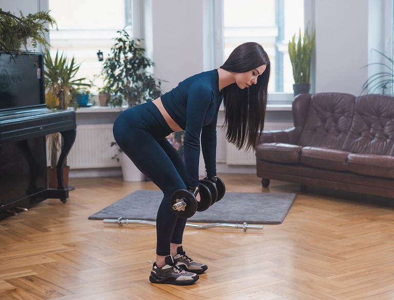 Lifter performing a dumbbell Romanian deadlift mid-rep with neutral spine