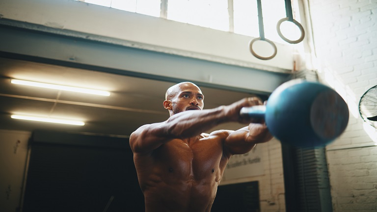 Muscular lifter performing a Russian kettlebell swing at chest height